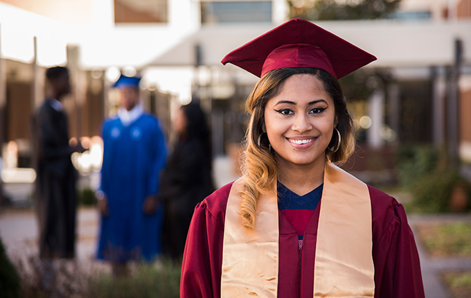 A female high school student in a graduation cap and gown.
