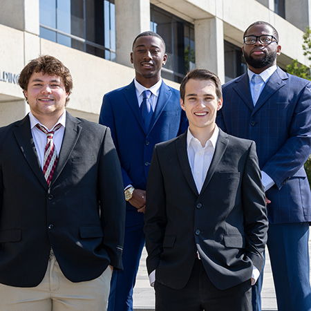 Four members of Future Coaches of America pose outside the Close-Hipp Building.