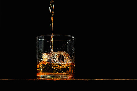 Bourbon being pored into a glass on an old wood table