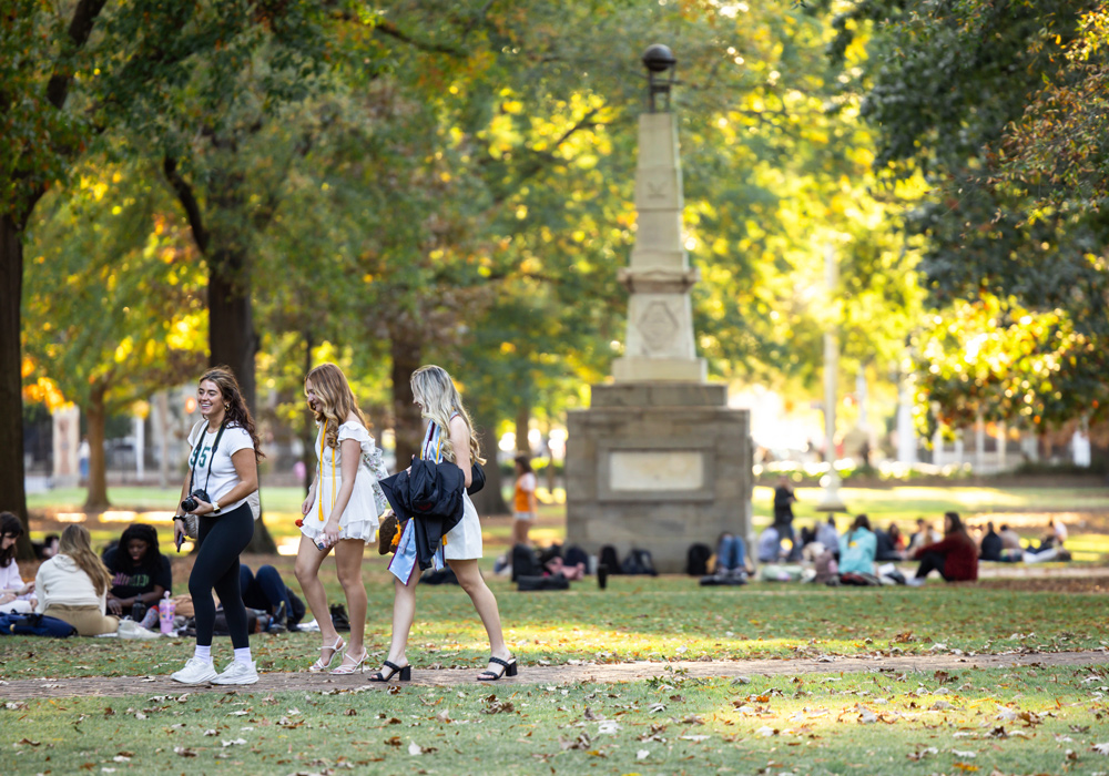 students on the horseshoe greenspace with an obelisk i the background